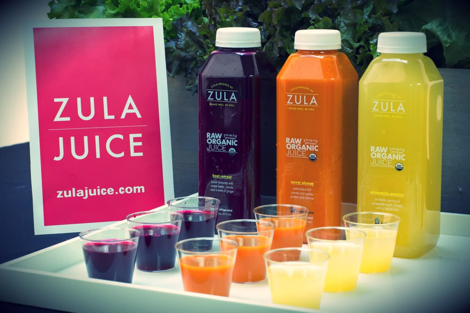 Zula tasting cups and bottles beside a pink Zula sign.